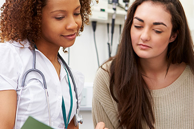 Una enfermera y una paciente leen juntas un folleto médico en una sala de examinación.5